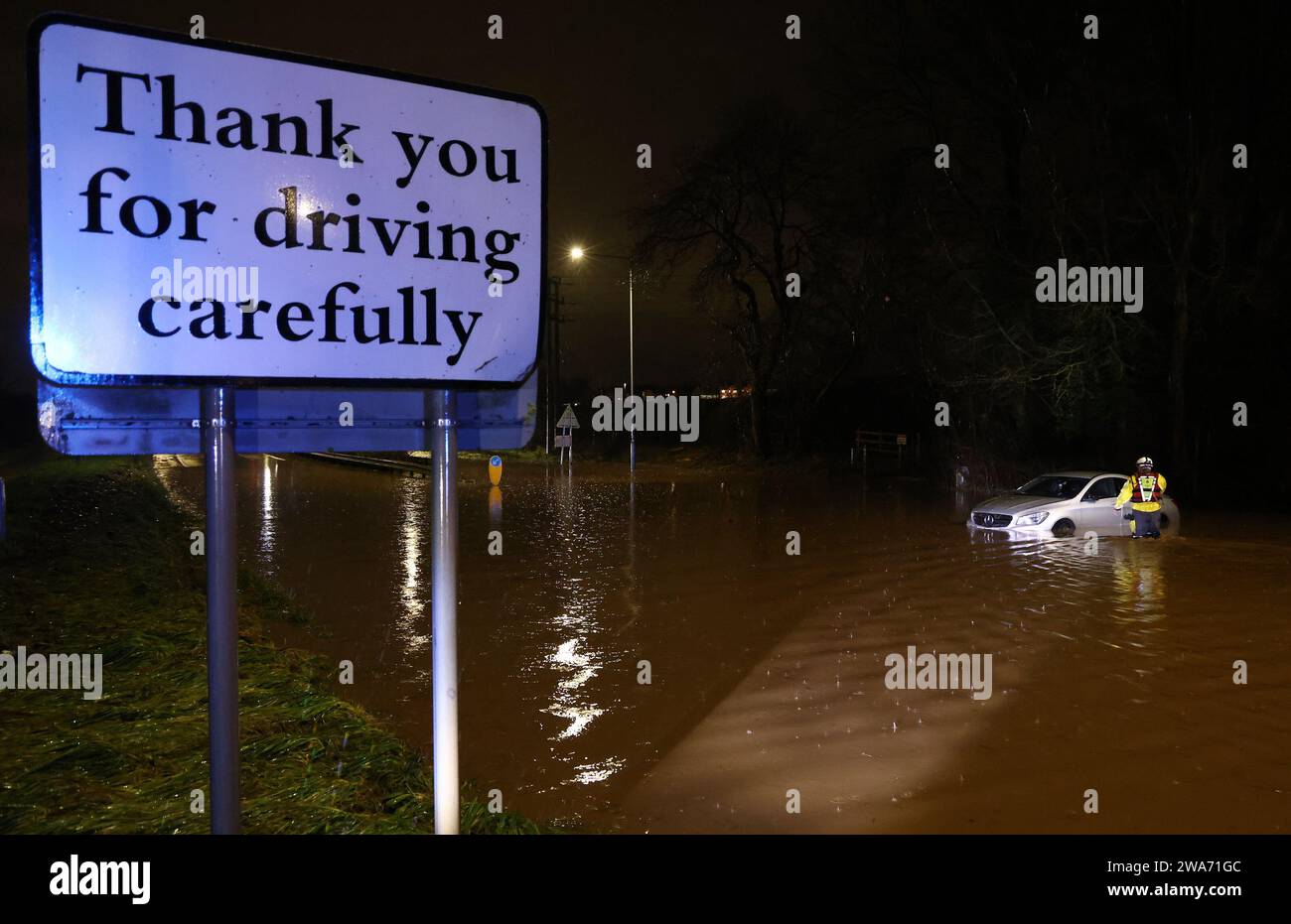 Hathern, Leicestershire, UK. 2nd January 2024. UK weather. A Fire Fighter checks inside a car stranded in flood water. High winds and heavy rain are battering a large swathe of the UK as the small but potent Storm Henk hits.  Credit Darren Staples/Alamy Live News. Stock Photo