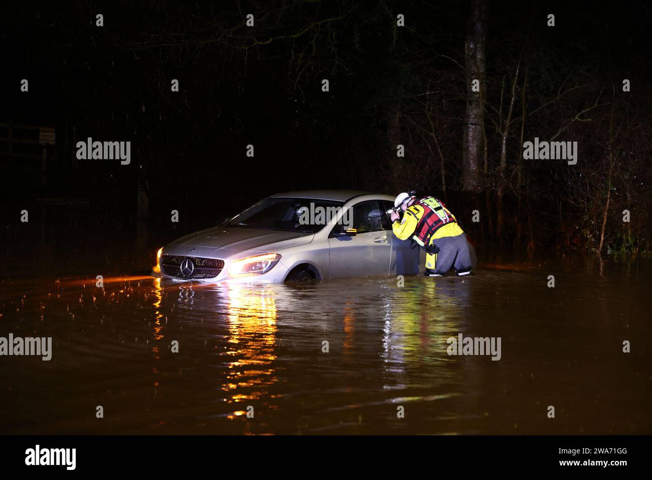 Hathern, Leicestershire, UK. 2nd January 2024. UK weather. A Fire Fighter checks inside a car stranded in flood water. High winds and heavy rain are battering a large swathe of the UK as the small but potent Storm Henk hits.  Credit Darren Staples/Alamy Live News. Stock Photo