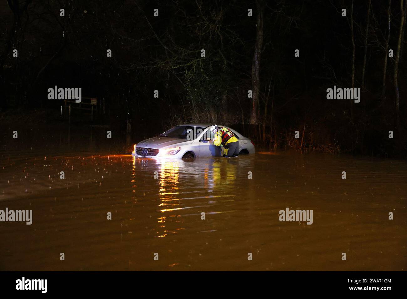 Hathern, Leicestershire, UK. 2nd January 2024. UK weather. A Fire Fighter checks inside a car stranded in flood water. High winds and heavy rain are battering a large swathe of the UK as the small but potent Storm Henk hits.  Credit Darren Staples/Alamy Live News. Stock Photo