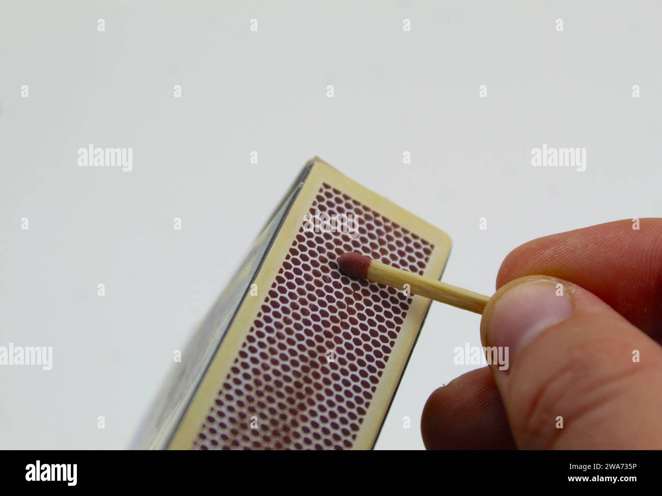 A close up photo of someone lighting a match against the side of a