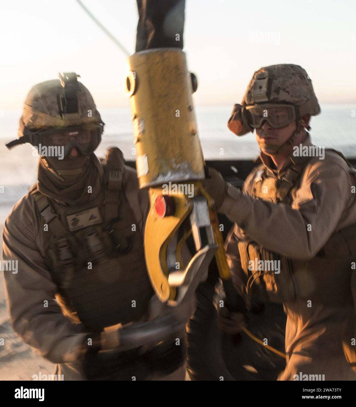 US military forces. 151029WC184-005 PINHEIRO DA CRUZ, PRAIA DA RAPOSA, Portugal – U.S. Marine Lance Cpl. Dustin Mason (left), a landing support specialists, with the Landing Support Detachment, 26th Marine Expeditionary Unit embarked aboard  the amphibious transport dock ship USS Arlington (LPD 24) prepares to attach a sling connected to a M105 trailer to a lifting hook from a CH-53E Super Stallion with Marine Medium Tilt rotor Squadron 162 (VMM-162), 26th MEU, embarked aboard the USS Arlington hovering overhead, while U.S. Marine Lance Cpl. Micah English (right), a landing support specialists Stock Photo