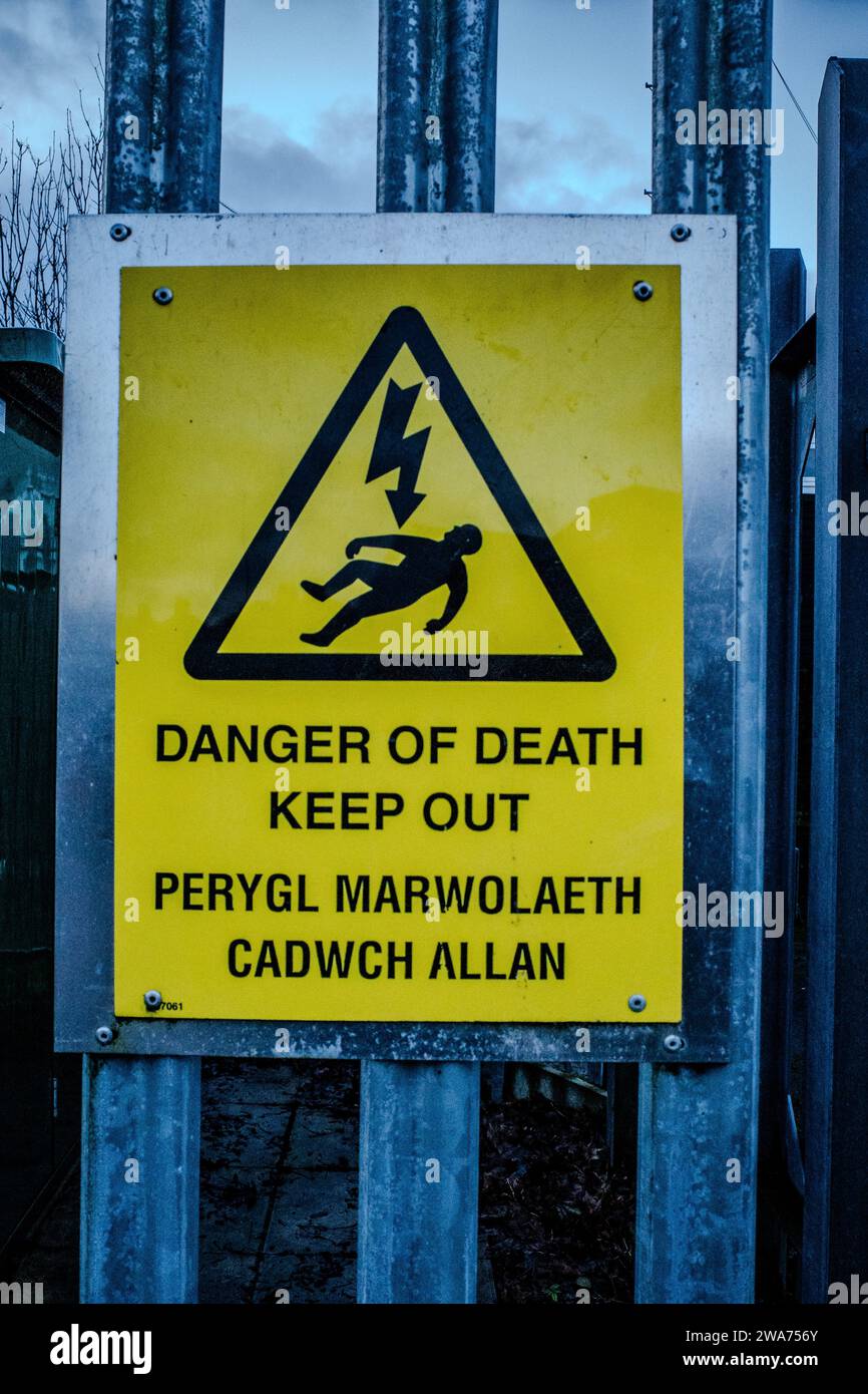 Danger of death warning sign mounted on an electricity transformer security fence. The wording is in both English and Welsh language. Stock Photo