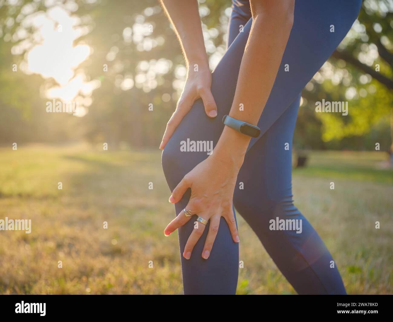 woman with knee pain in evening park. hold her sports injured knee. Low