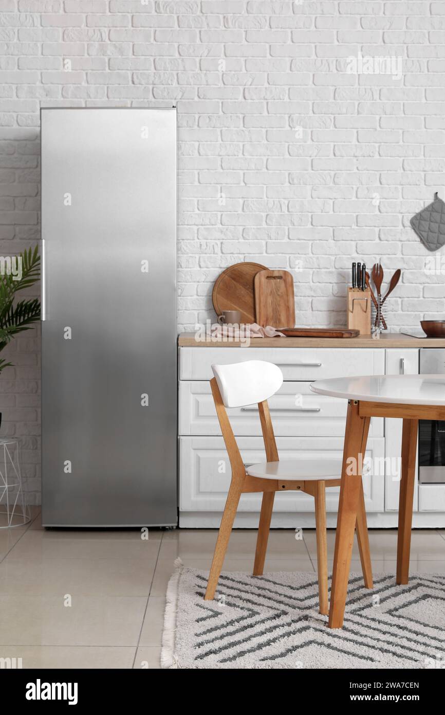 Interior of light kitchen with white counters, fridge and dining table ...