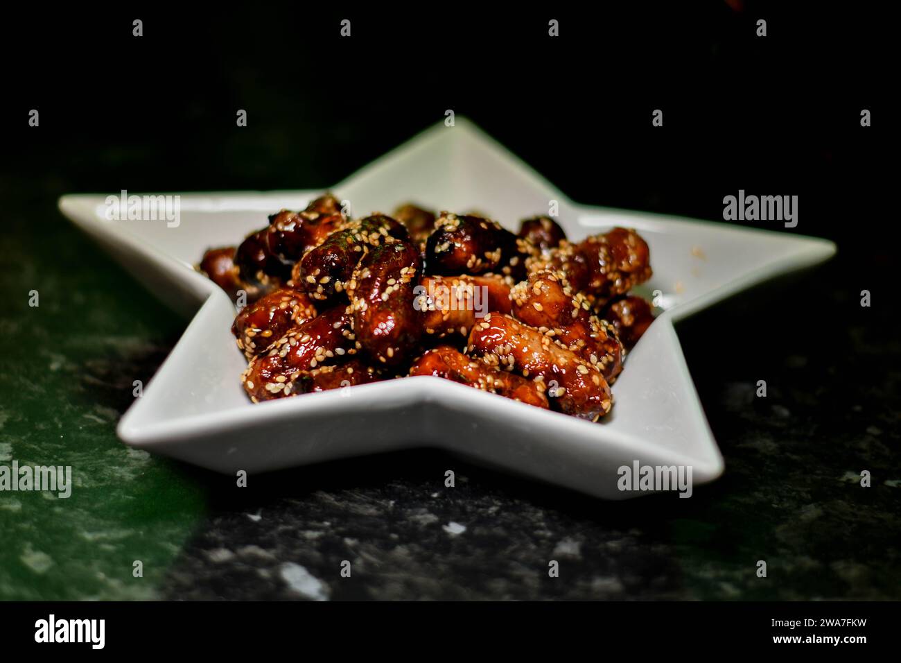 Cocktail sausages covered in sesame seeds on a star shaped dish Stock