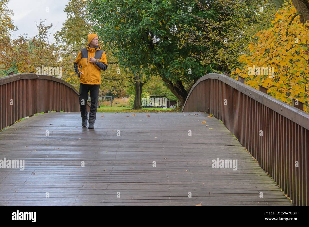 Autumn, bridge and a man in a yellow jacket. Stock Photo