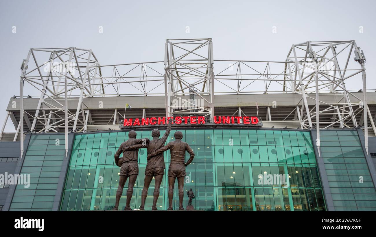 United Trinity statue featuring Manchester United legends George Best, Denis Law and Sir Bobby Charlton pictured facing Old Trafford stadium in Manche Stock Photo