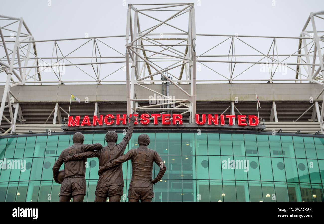 United Trinity statue featuring Manchester United legends George Best, Denis Law and Sir Bobby Charlton pictured facing Old Trafford stadium in Manche Stock Photo