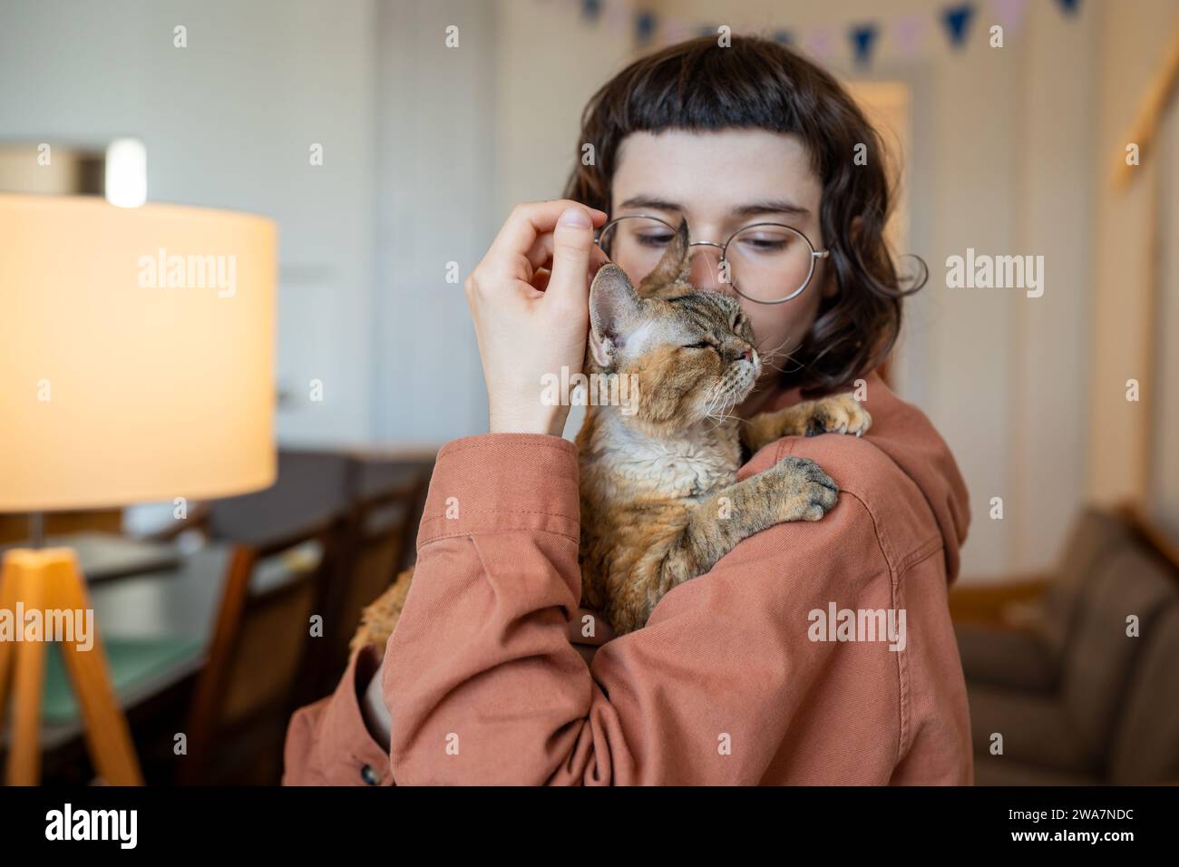Cat owner caring woman hug kissing holding in hands loving pet at home