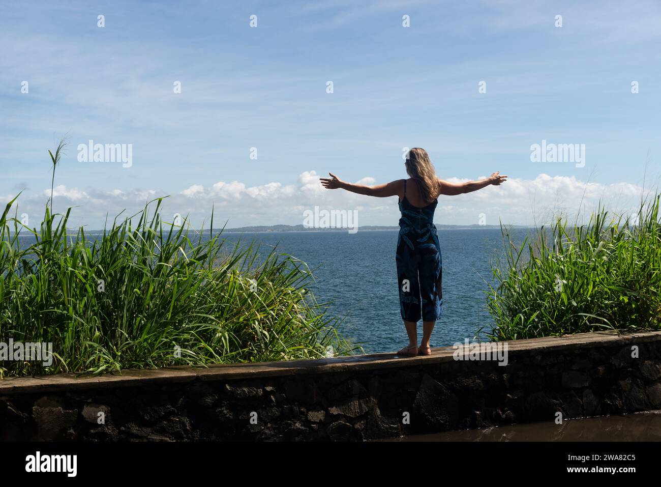 A woman, tourist, standing with her back to the camera with her arms ...