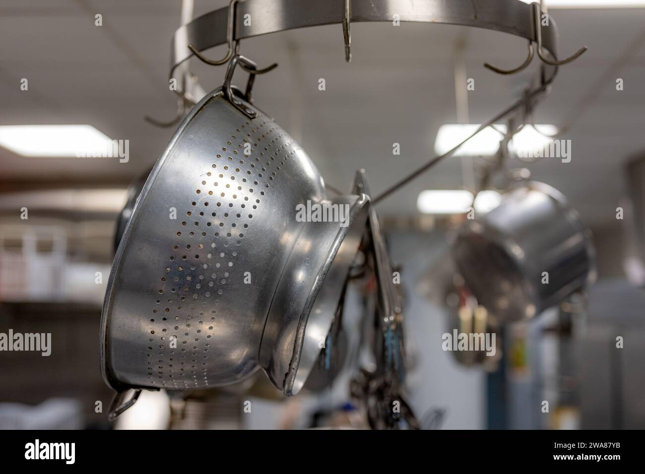 Stainless steel pots and pans and other cooking utensils hanging in a ...