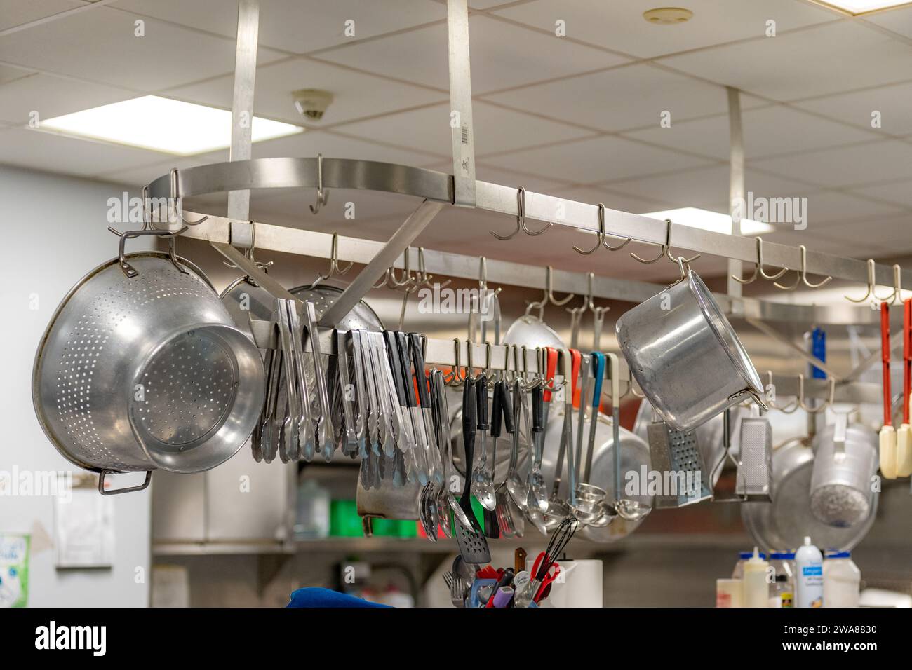 Stainless steel pots and pans and other cooking utensils hanging in a ...