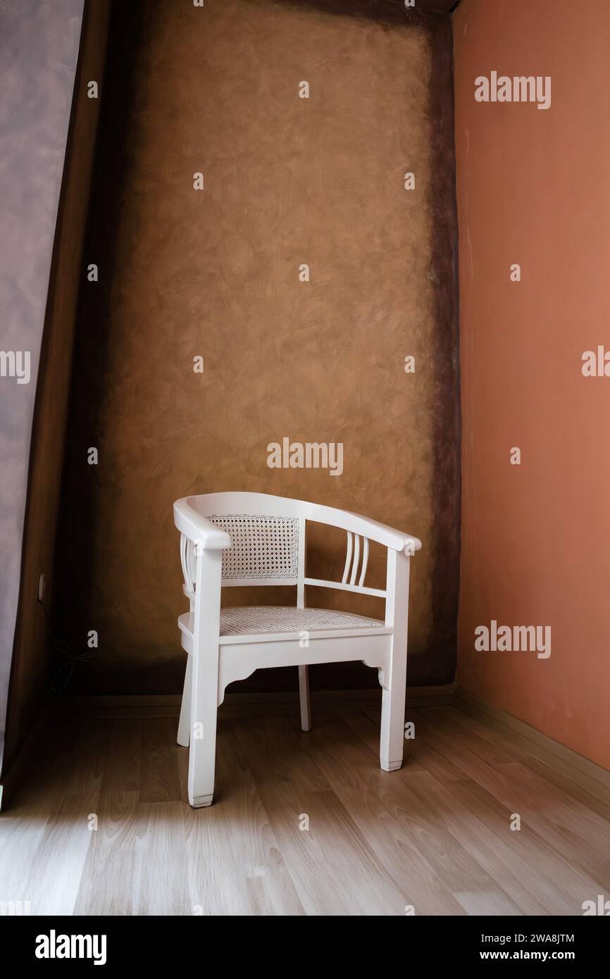 white wooden chair in the corner of a room with a wooden floor Stock Photo