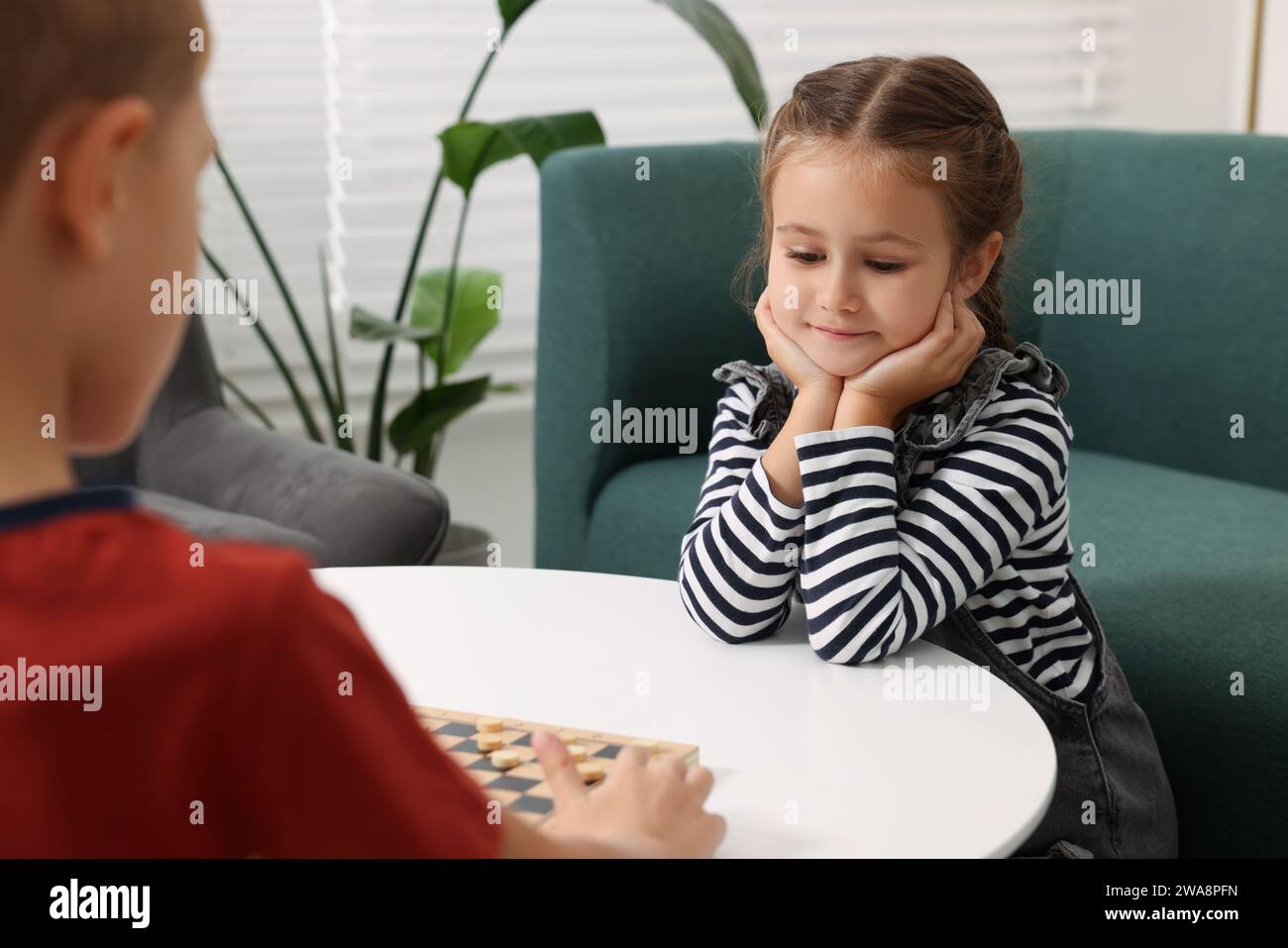 Children playing checkers at coffee table in room Stock Photo - Alamy