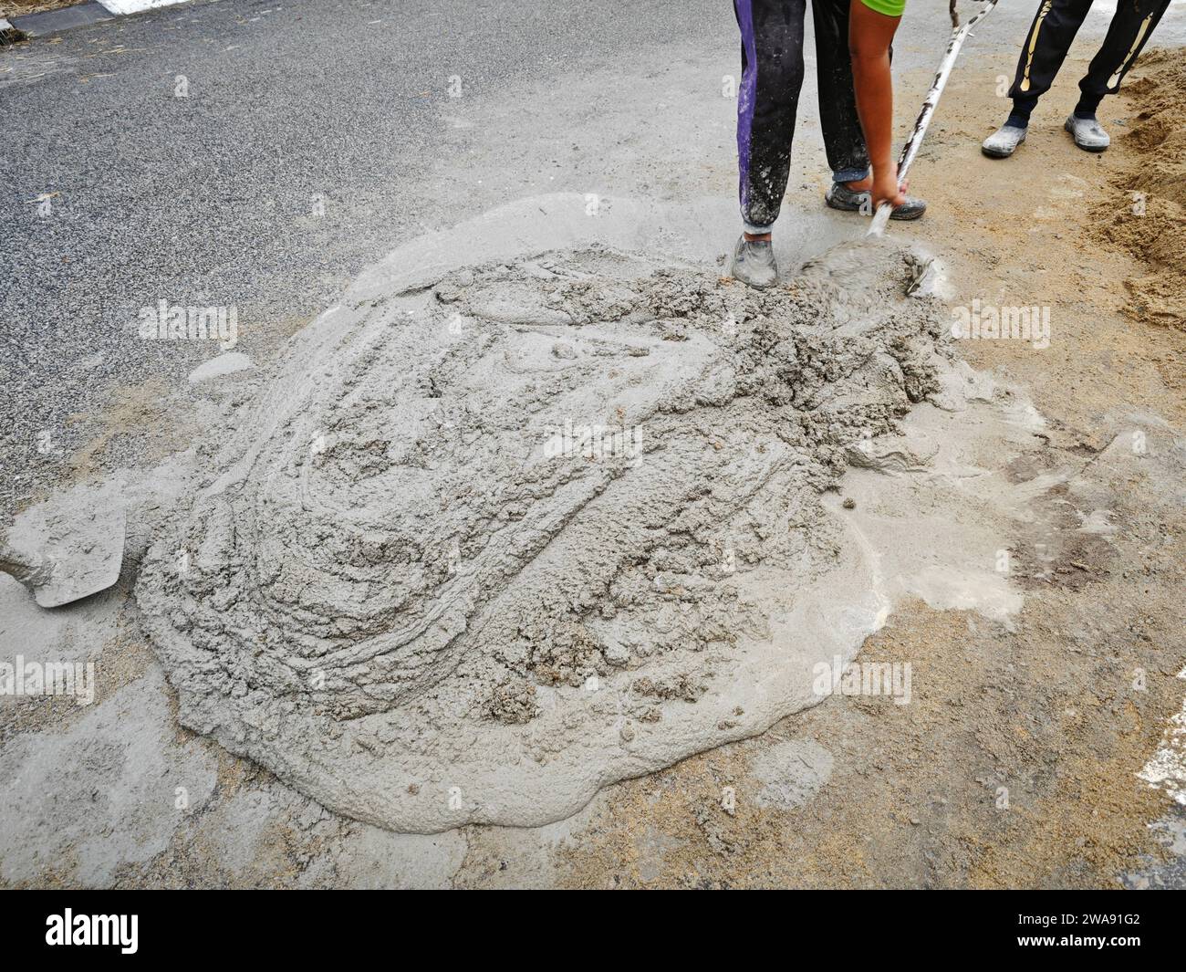 manually mixing cement and sand with shovel to make mortar Stock Photo
