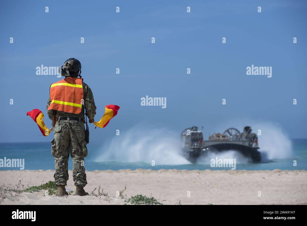 US military forces. 180307TK177-0291 HAIFA, ISRAEL (March 7, 2018) Logistics Specialist Seaman Denny Figueroa, from Bayamon, Puerto Rico, and assigned to Beach Master Unit (BMU) 2, signals Landing Craft, Air Cushion 67, attached to Assault Craft Unit (ACU) 4, as it prepares to make landfall on the beach in Israel, March 7, 2018. The Wasp-class amphibious assault ship USS Iwo Jima (LHD 7), homeported in Mayport, Florida, is participating in Juniper Cobra 2018 and conducting naval operations in the U.S 6th Fleet area of operations. JC18 is a computer-assisted exercise conducted through computer Stock Photo