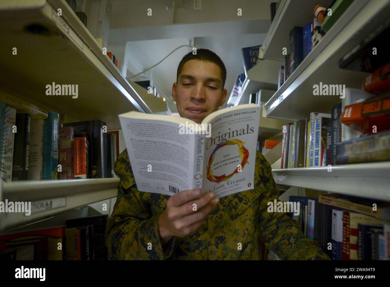 US military forces. 180430AT135-023 PACIFIC OCEAN (April 30, 2018) Marine Corps Lance Cpl. Bryan Pena, assigned to 1st Light Armored Reconnaissance (LAR), reads a book in the library aboard the Wasp-class amphibious assault ship USS Essex (LHD 2) during Essex Amphibious Ready Group (ARG) and 13th Marine Expeditionary Unit (MEU) exercise (ARGMEUEX). ARGMEUEX enhances joint integration, lethality and collective capabilities of the Navy-Marine team through joint planning and execution of challenging and realistic training scenarios. (U.S. Navy photo by Mass Communication Specialist 3rd Class Matt Stock Photo