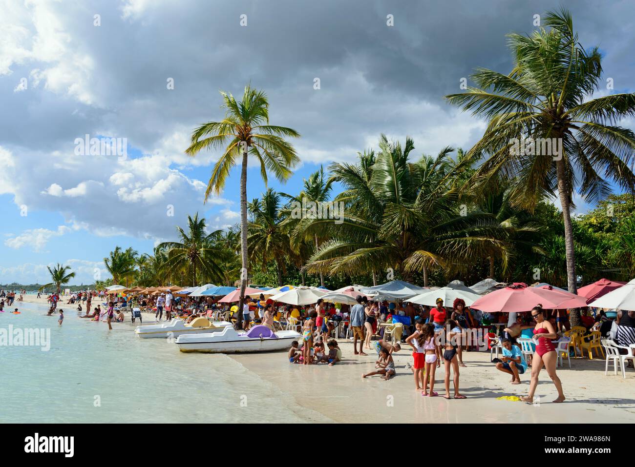 Beachgoers relax under colourful umbrellas next to the calm sea, Boca ...