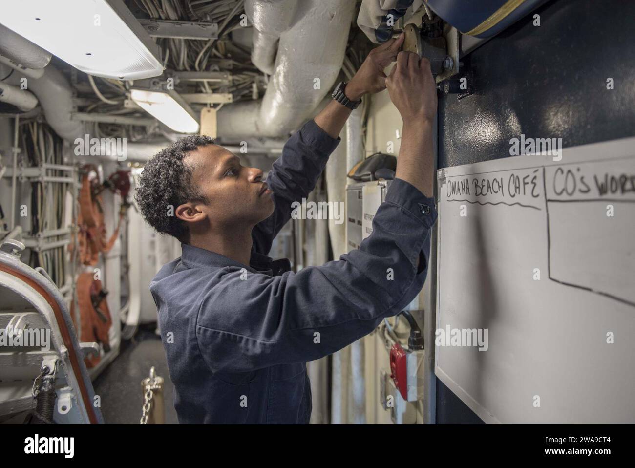 US military forces. 180622DZ642-0022 MEDITERRANEAN SEA (June 22, 2018) Electrician's Mate 1st Class Joshua Dowell troubleshoots an electrical circuit aboard the guided-missile cruiser USS Normandy (CG 60). Normandy is currently deployed as part of the Harry S. Truman Carrier Strike Group. With Harry S. Truman as the flagship, deploying strike group assets include staffs, ships and aircraft of Carrier Strike Group (CSG) 8, Destroyer Squadron (DESRON) 28 and Carrier Air Wing (CVW) 1; as well as the Sachsen-class German Frigate FGS Hessen (F 221). (U.S. Navy photo by Mass Communication Specialist Stock Photo