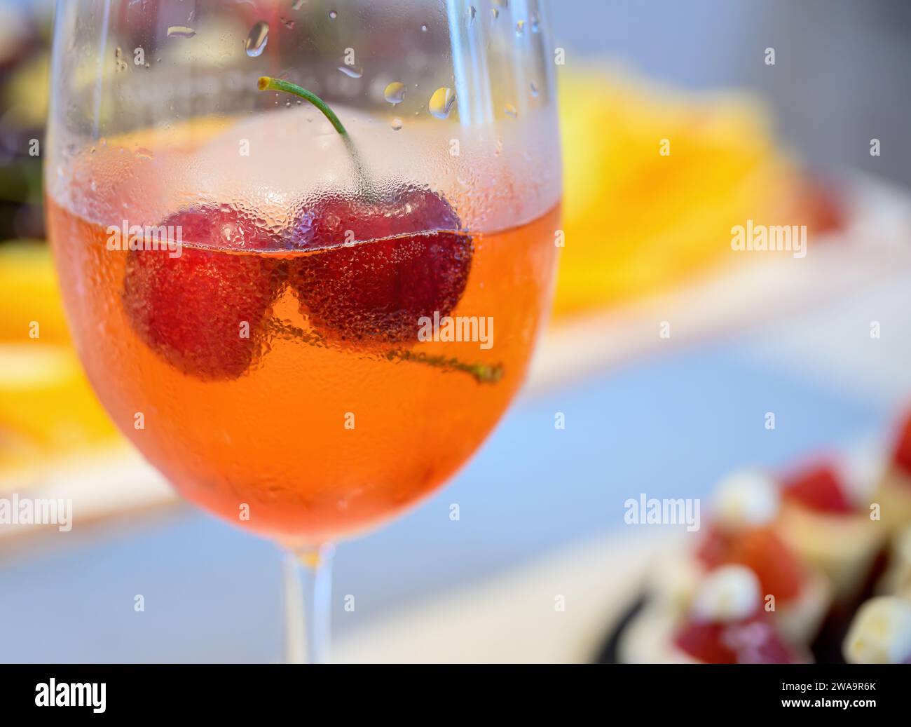 Ice cold fresh cocktail drinks with cherries. Glass covered with water drops condensation. Out-of-focus dessert background. Stock Photo