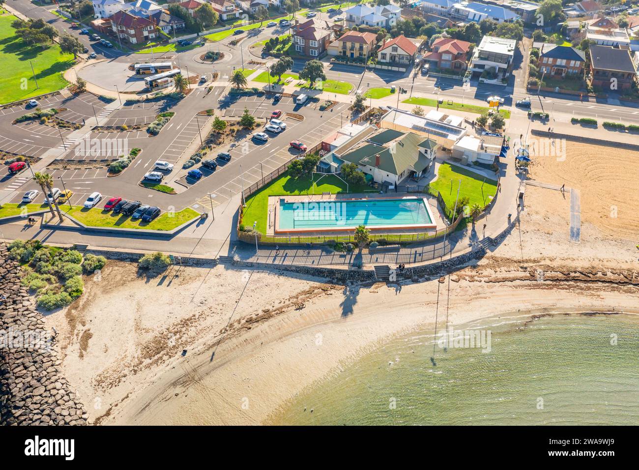 Aerial view of a coastal swimming pool between a carpark and a sandy