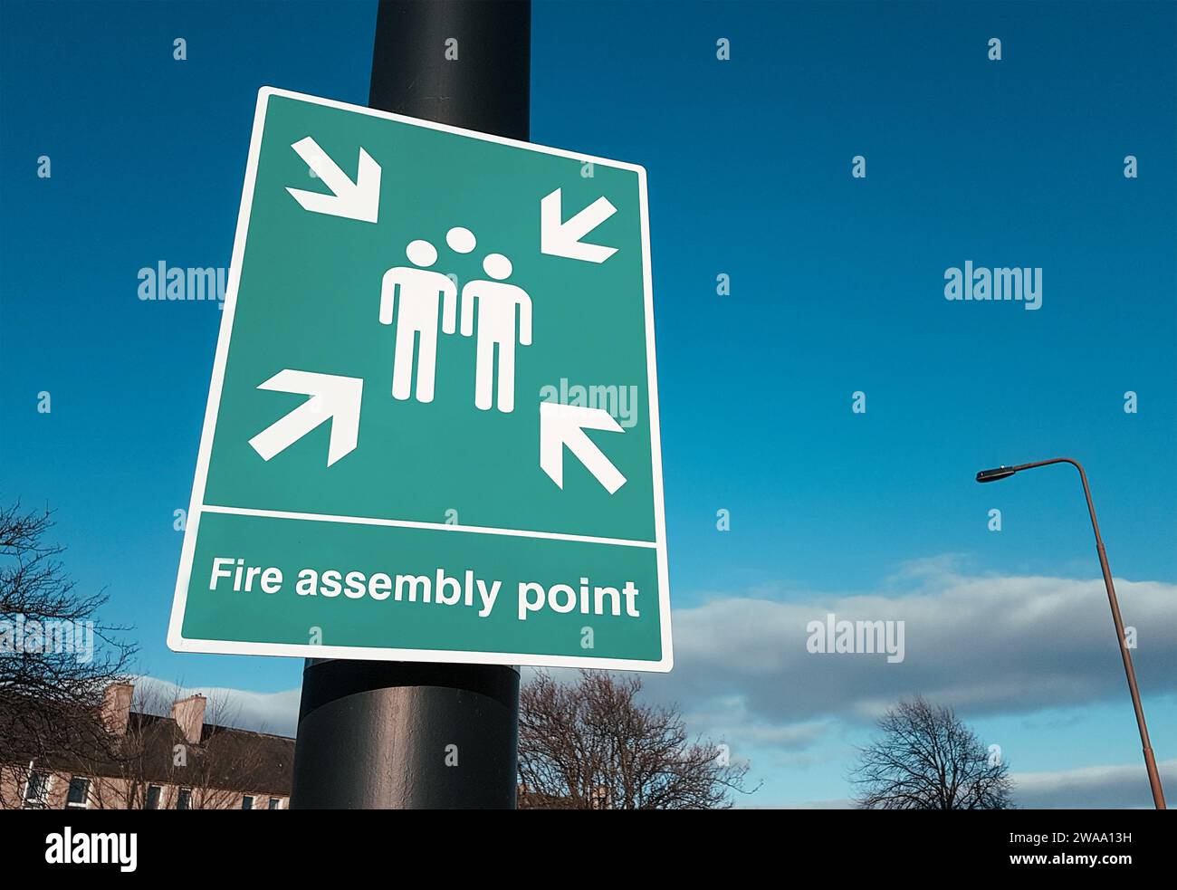 Fire assembly point sign, green background with white text and symbols Stock Photo Alamy