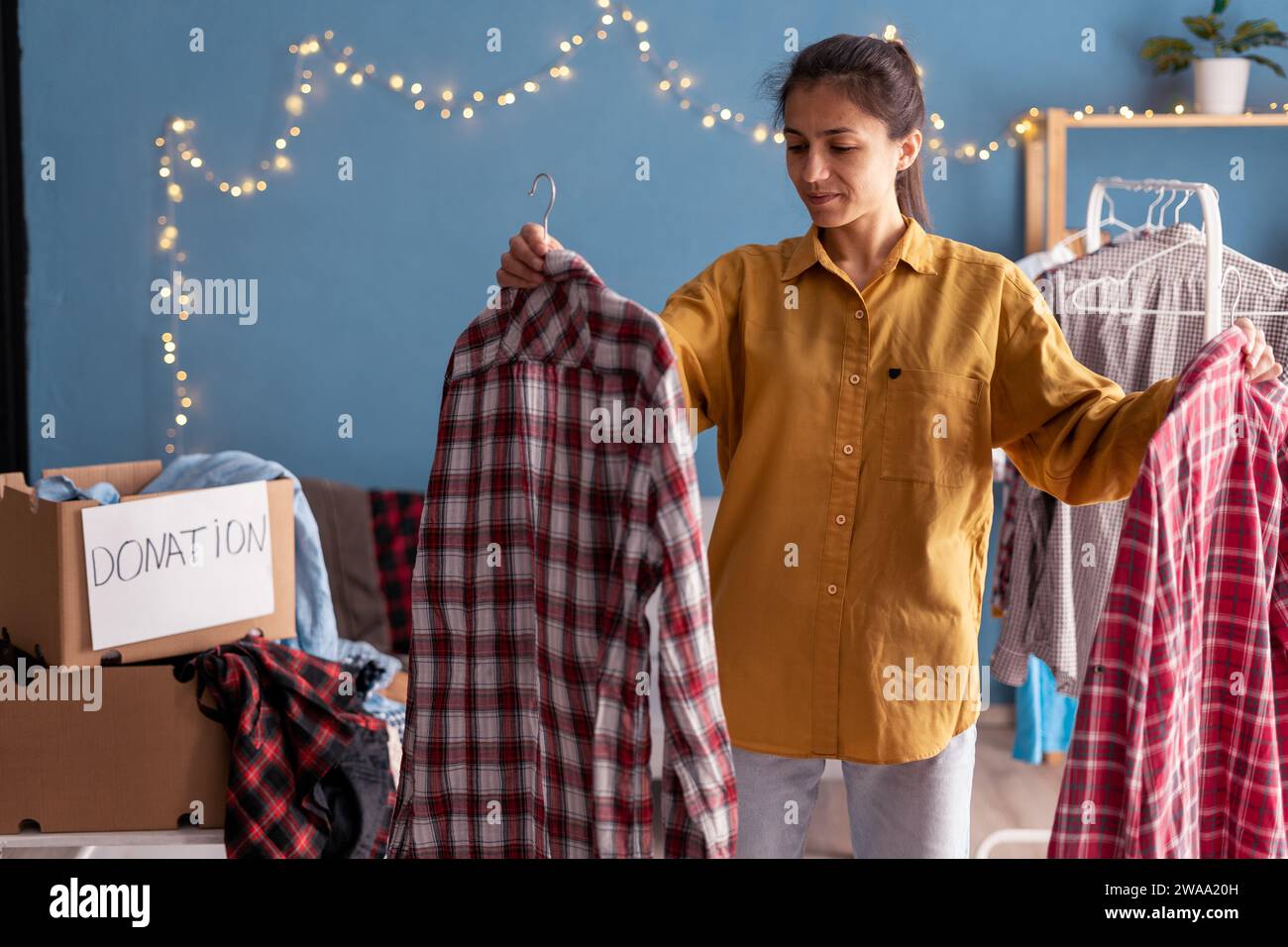 Hispanic beautiful woman packing clothes into donation box in living