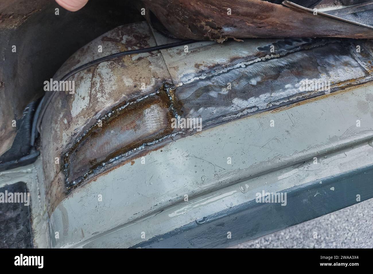 Welding a car or van inner fender. Repairing rust holes with a welding machine, welding job. Patching metal plates over the hole. Step four Stock Photo