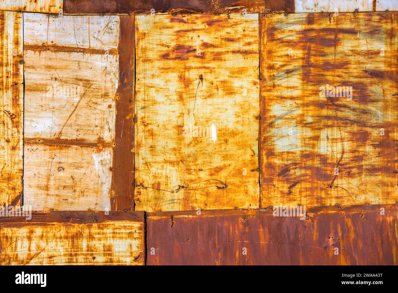 rusty steel sheets welded together wall patchwork with leftovers of faded white paint, closeup full-frame background and texture Stock Photo