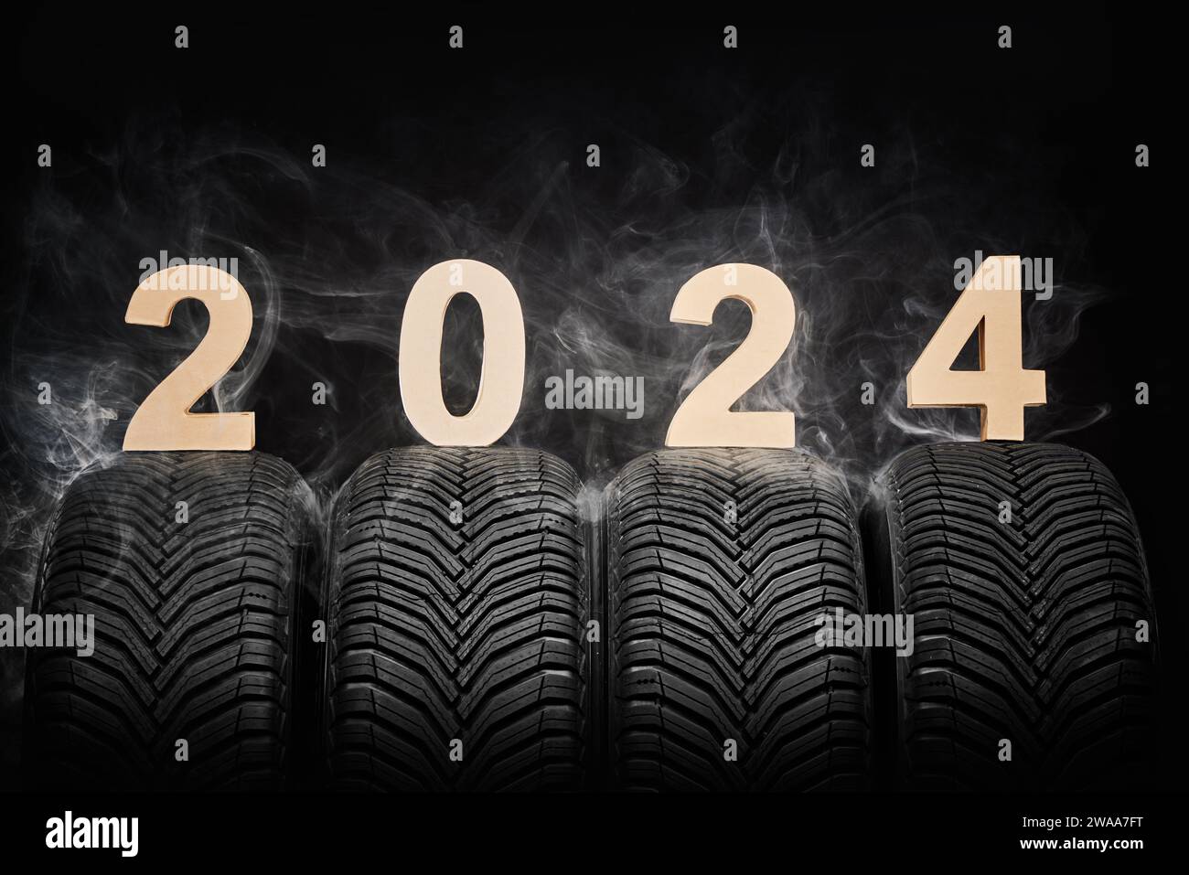 Car tires, winter wheels, isolated new tyres, fog and happy new year 2024 black background . Stock Photo