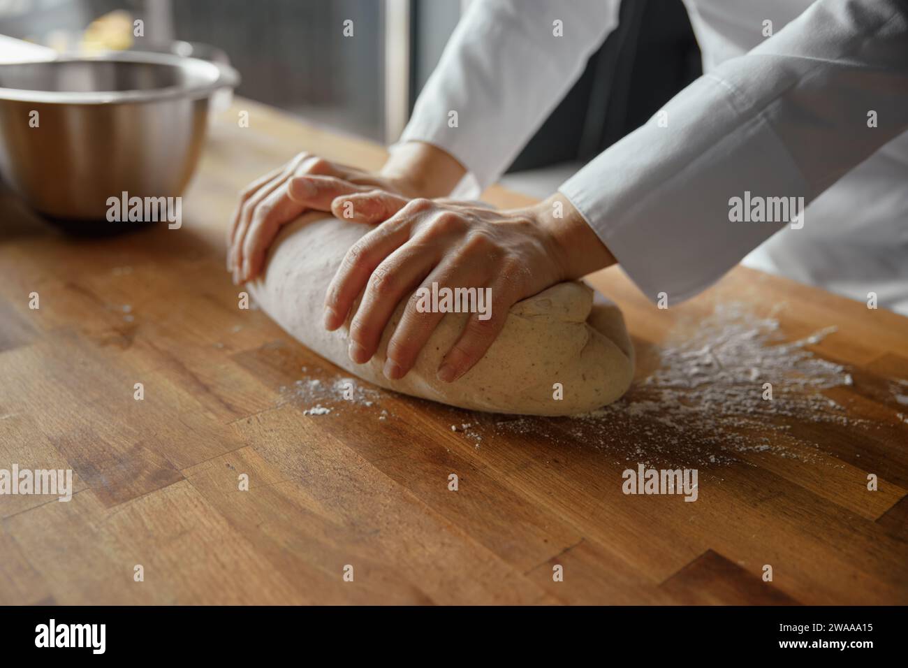 Woman baker wearing uniform kneading dough at kitchen Stock Photo - Alamy