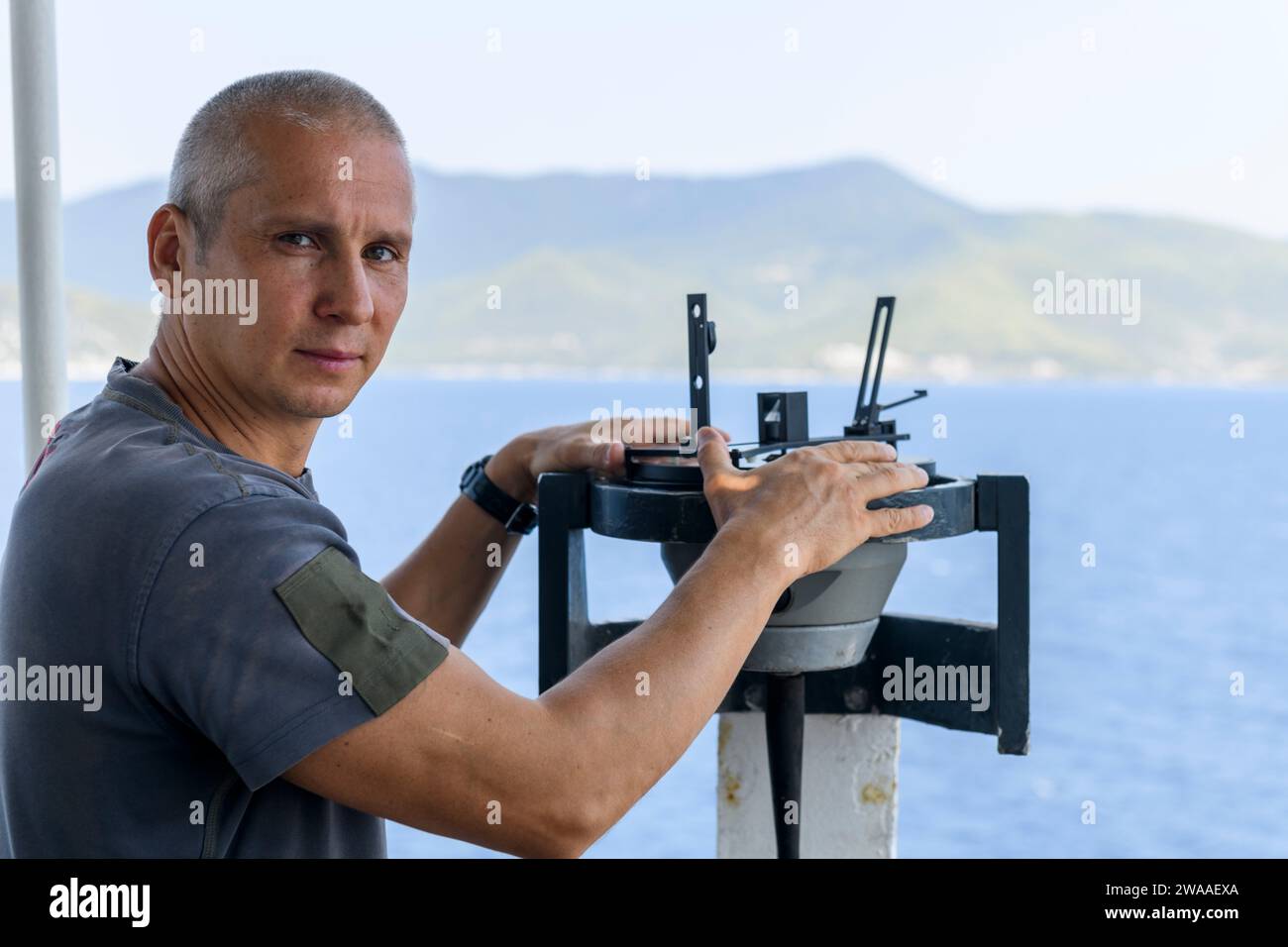 Navigational officer taking bearing with azimuth ring on gyro compass