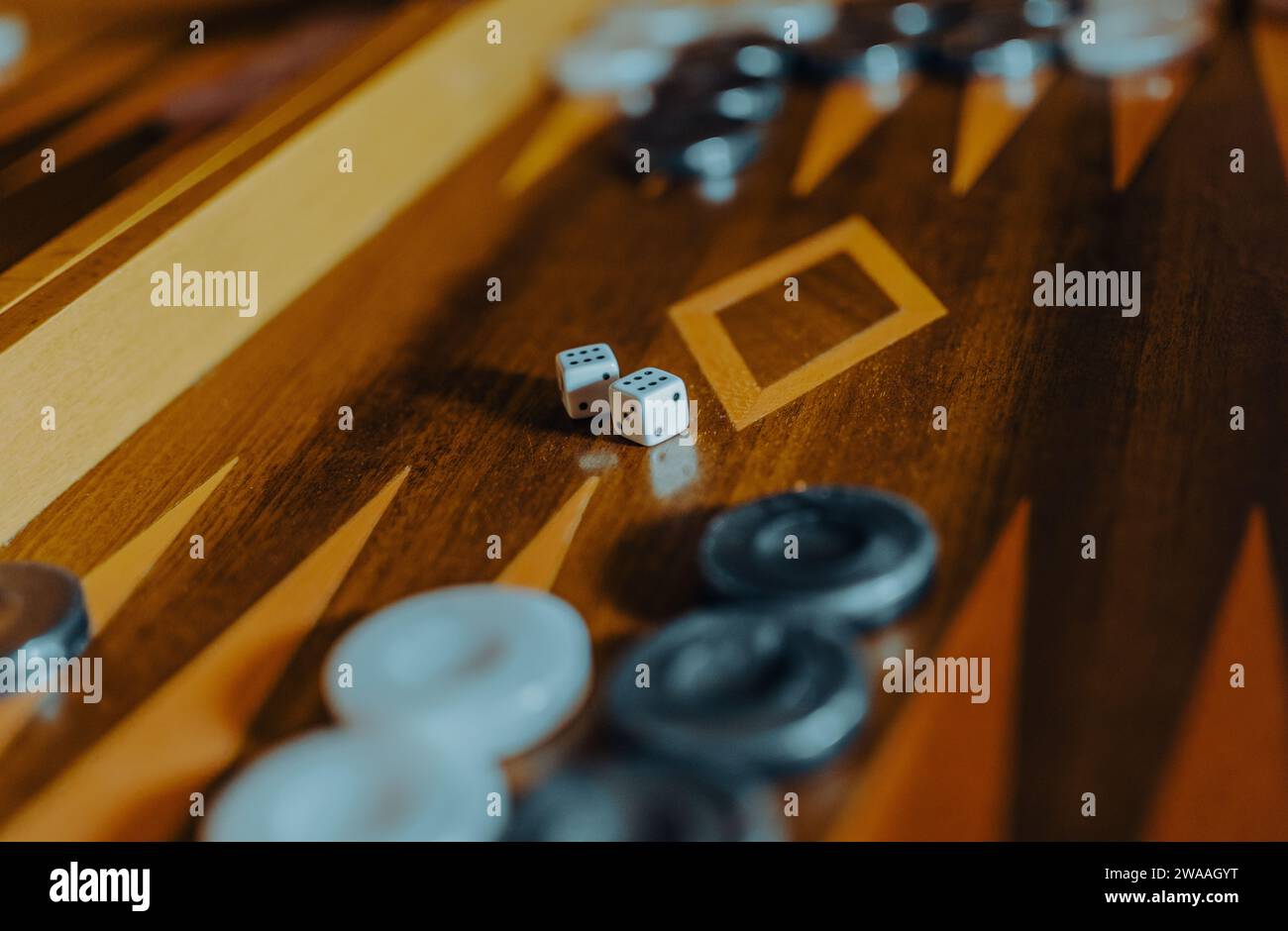 Backgammon board with dice and playing pieces in warm light, shallow depth of field. Stock Photo