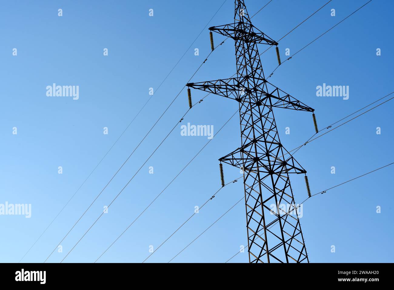 High-voltage power lines against a blue sky background. Towers for the transmission of electricity. Power transmission lines. Stock Photo