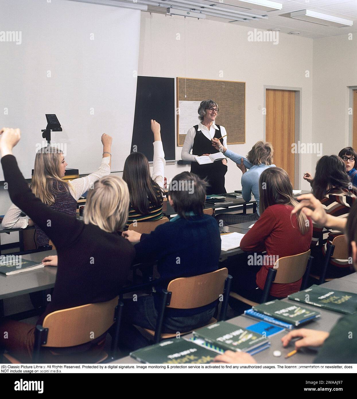 In the 1970s. A school class sits in the benches during a lesson with a