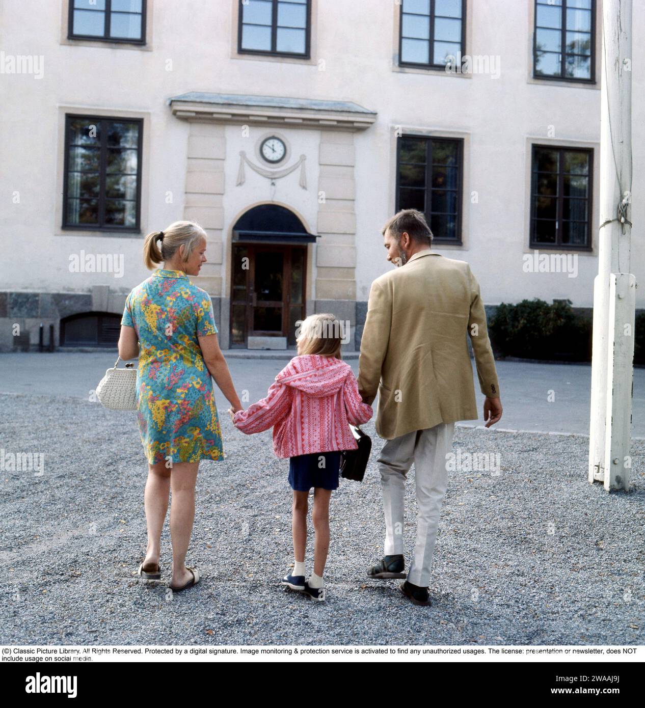 1960s parents. A mother and father are accompanying their daughter on her first day in school. 1969 Stock Photo