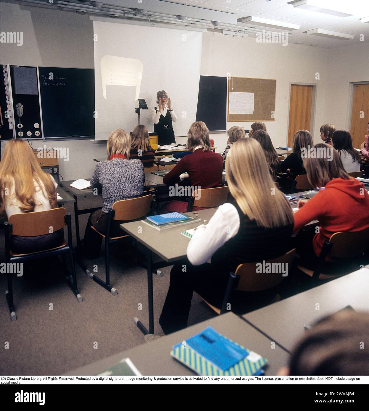 In the 1970s. A school class sits in the benches during a lesson with a