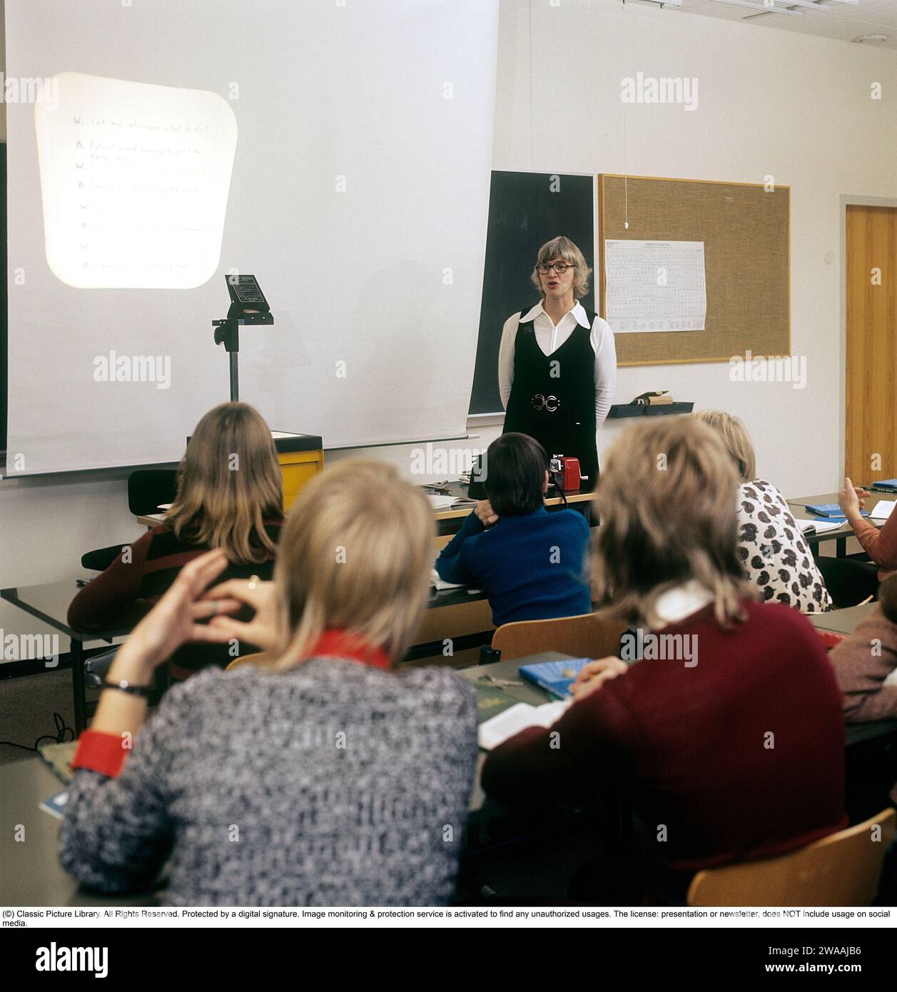 In the 1970s. A school class sits in the benches during a lesson with a