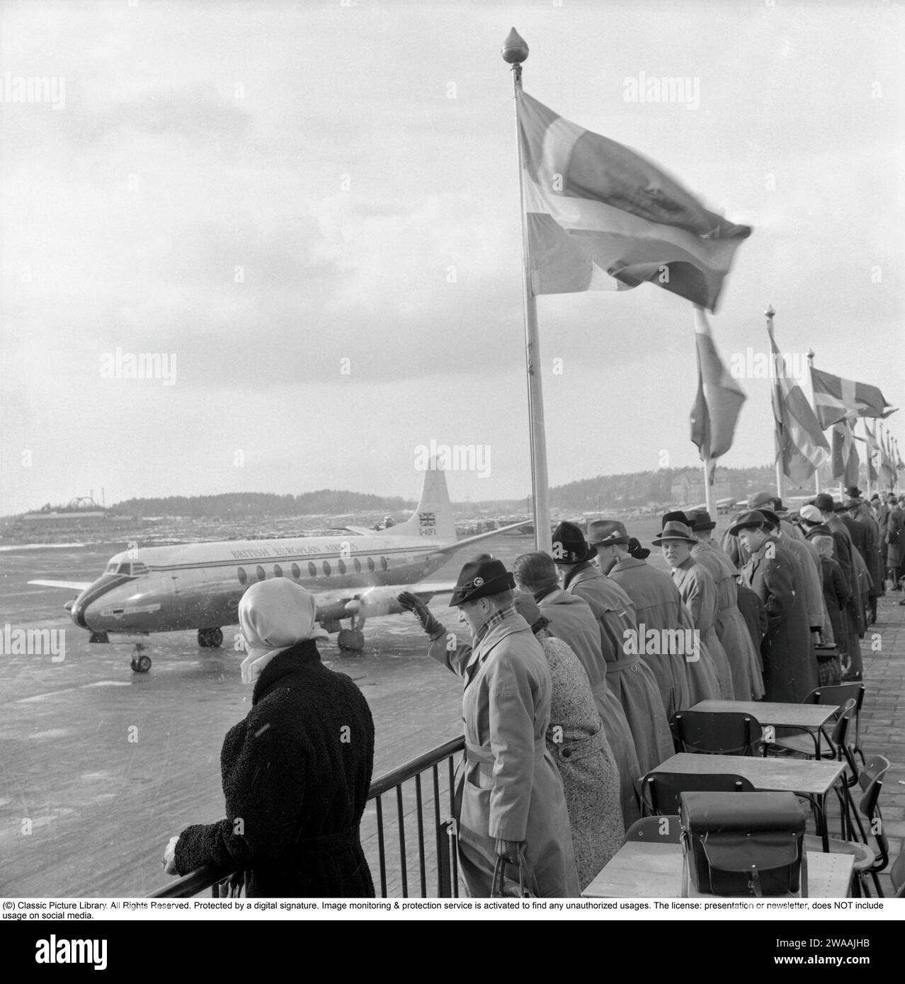 1950s airport. People are standing on an outdoor terrace overviewing the aircrafts waving goodbye to someone. Sweden 1956 Stock Photo