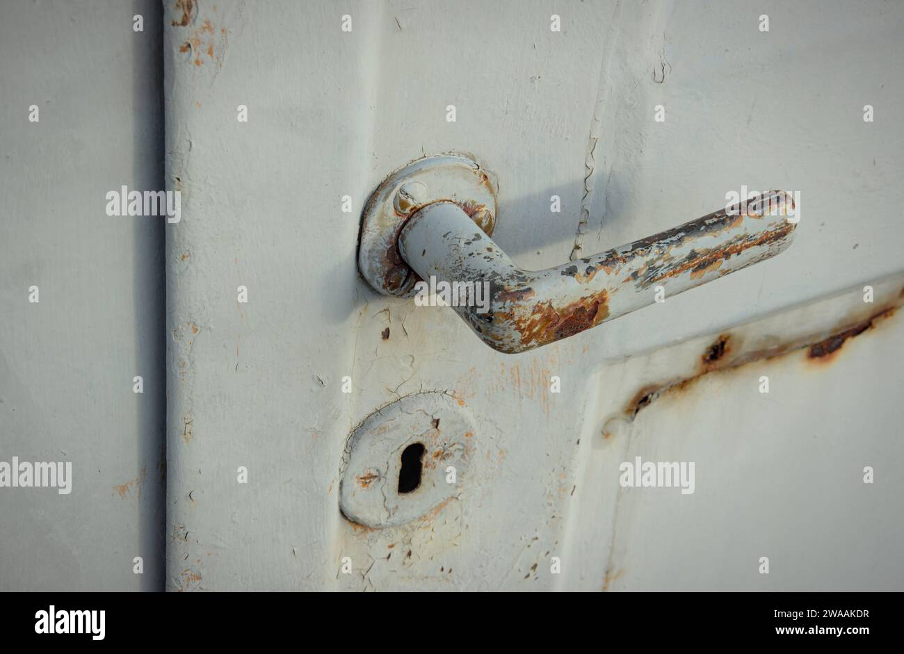 Rusty door opener. Old door latch of a garage. Doorknob with shadows. Stock Photo