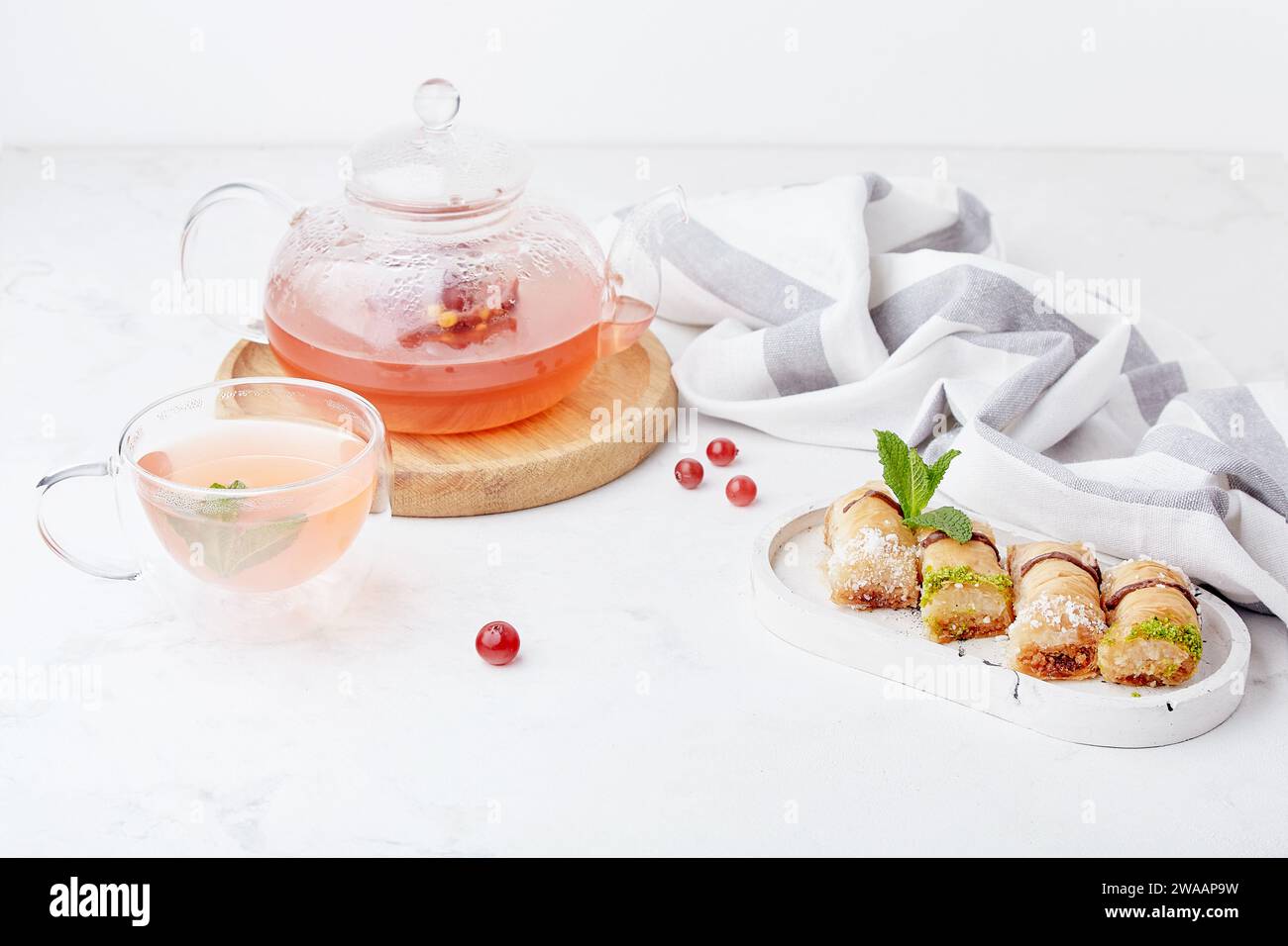 Aesthetic autumn glass teapot of natural healthy cranberry tea and traditional turkish baklava. Lagom home Stock Photo