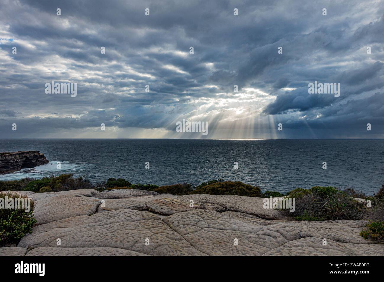 Sun rays shining through hole in the clouds over the sea, just after sunrise, between Maroubra Beach and Malabar Beach, Randwick, Sydney, Australia. Stock Photo