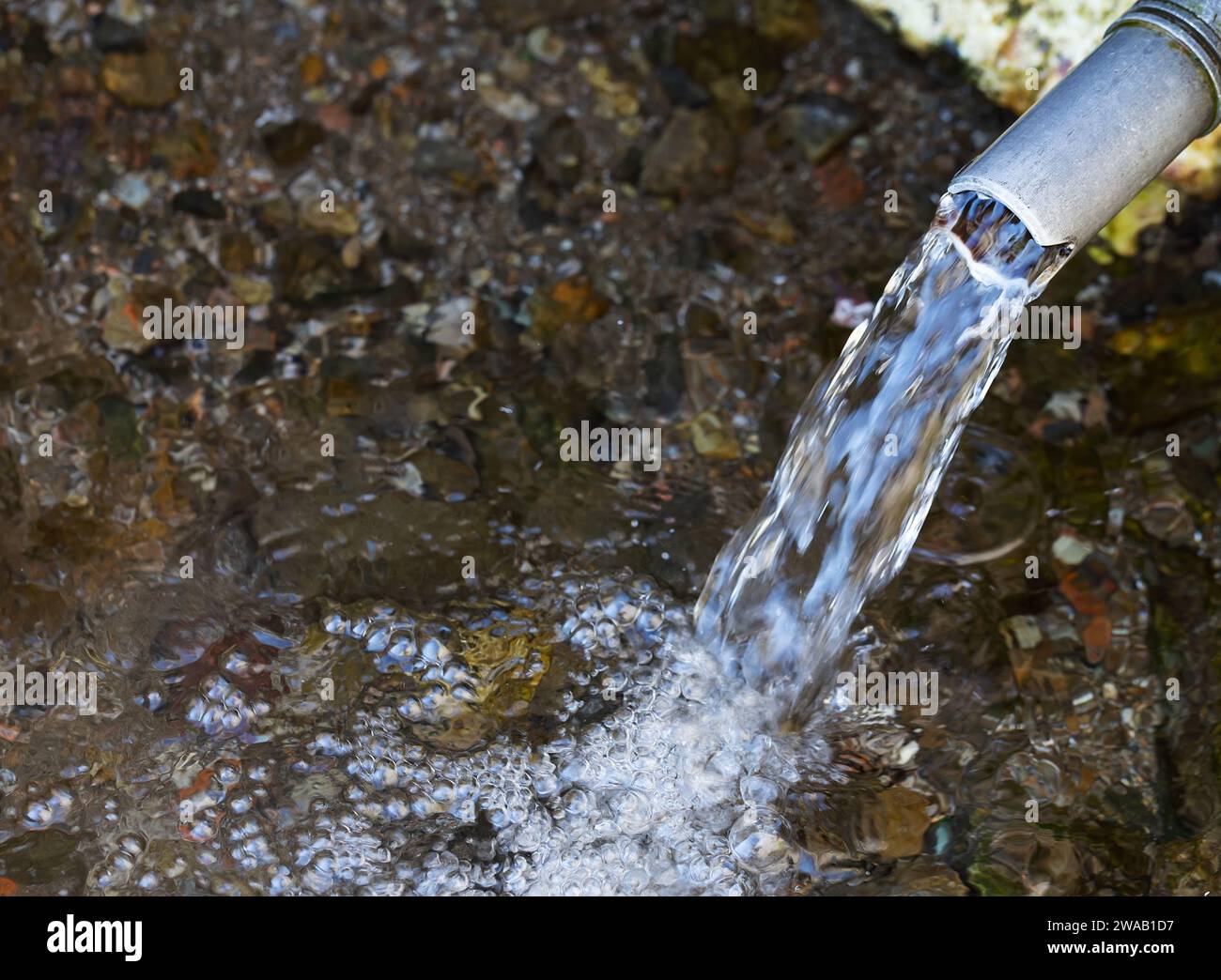 Fresh water emerging from a pipe. Image illustrating water scarcity and importance of fresh clean water in the environment. Stock Photo