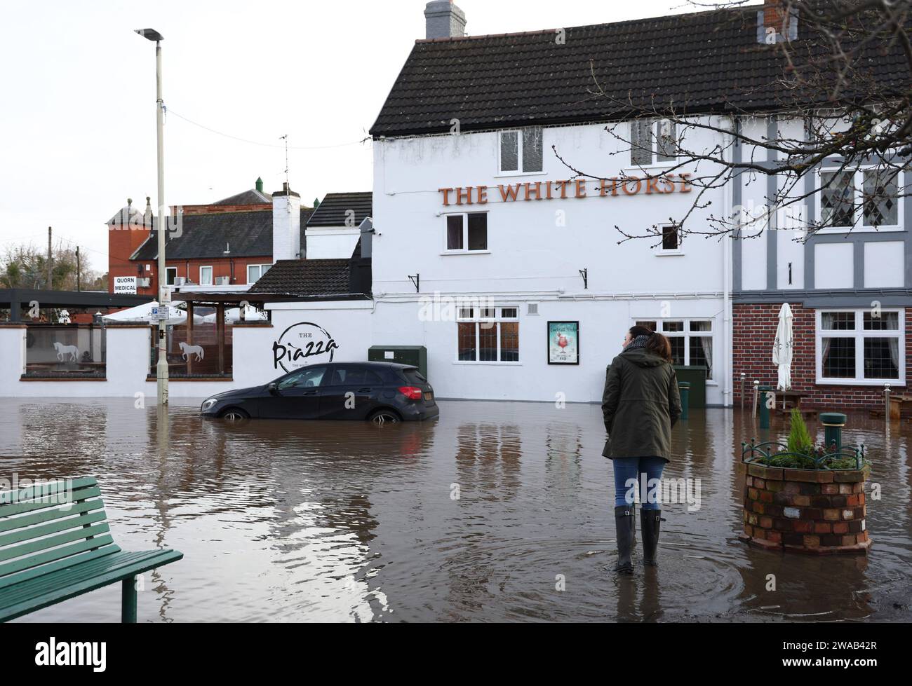 Quorn, Leicestershire, UK. 3rd January 2024. UK weather. A woman looks at a pub sitting in flood water. Heavy rain and wind has battered large swathes of the UK after the small but potent Storm Henk hit.  Credit Darren Staples/Alamy Live News. Stock Photo