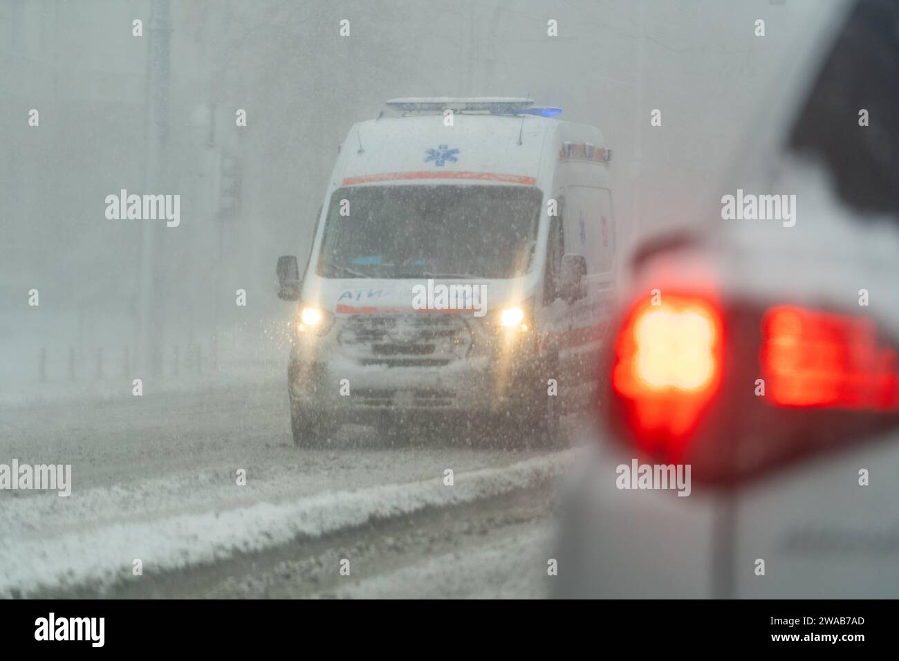 Ambulance navigating through heavy snow in the city, daylight emergency Stock Photo