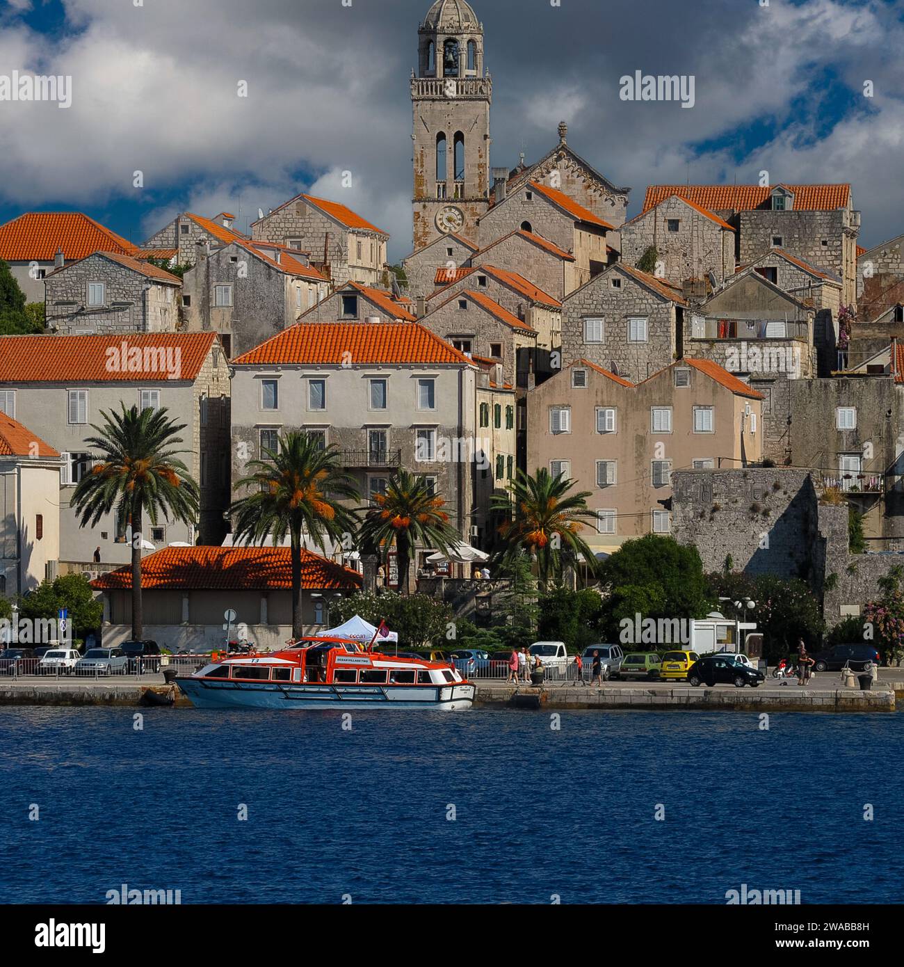 The campanile of the Cathedral of St Mark rises above red roofs in the town of Korčula in Dubrovnik-Neretva county, Croatia.  Also visible in this image is the apex of the cathedral’s western gable, its sumptuous decoration added in the later 1400s. Stock Photo