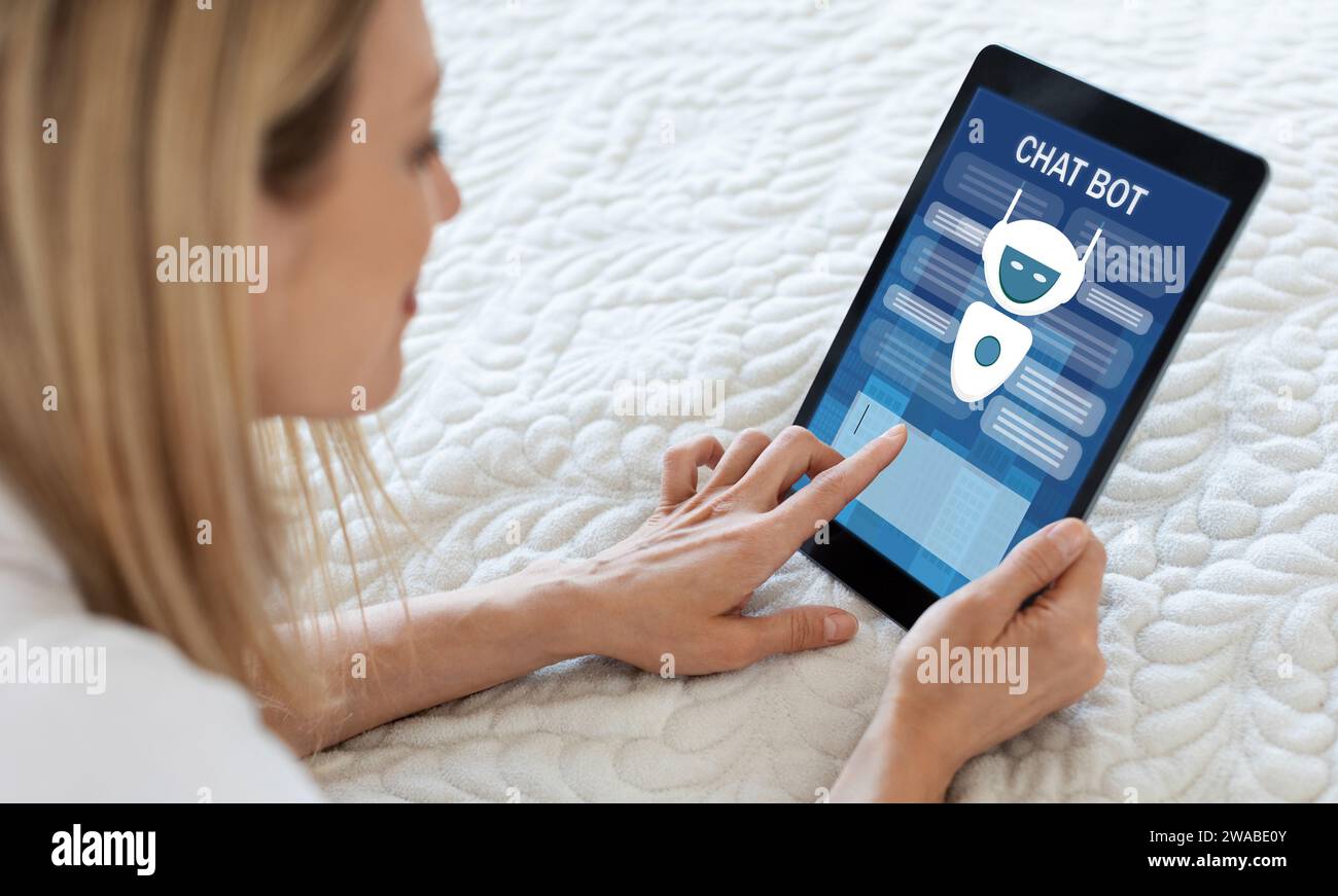Blonde woman using chatbot on digital tablet, home interior Stock Photo