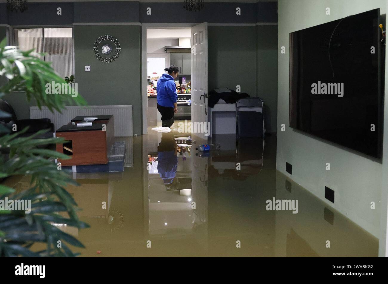 Loughborough, Leicestershire, UK. 3rd January 2024. UK weather. A woman walks through her flooded home on the Belton Road. Heavy rain has battered a large swathe of the UK as the small but potent Storm Henk hit.  Credit Darren Staples/Alamy Live News. Stock Photo