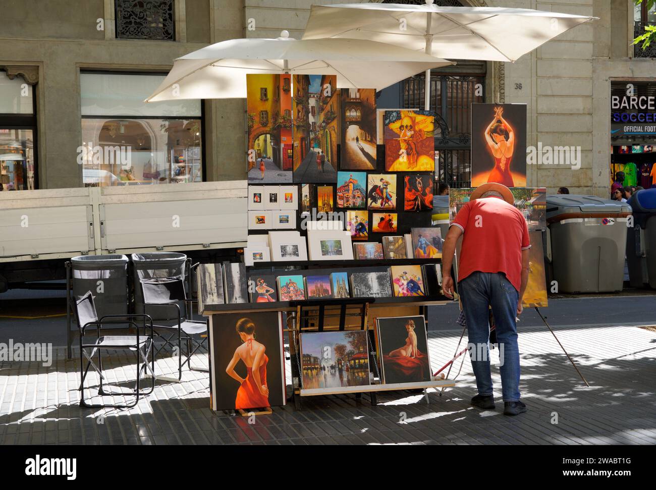 Barcelona, Spain - May 26, 2022: Painter who sells his art on the street and paints for hire, street stall with umbrellas and stands for his paintings Stock Photo
