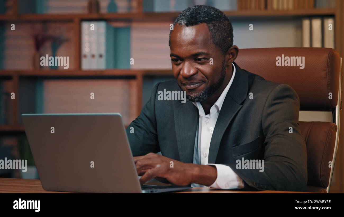 African american businessman check email read good news on laptop excited happy man leader rejoice in victory celebrating success get new opportunity Stock Photo